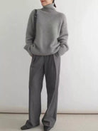 Person wearing a gray sweater and pants against a white background