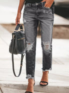 NEWYORKLISTED STYLE COLLECTION: Person wearing distressed gray jeans with a black handbag on a blurred background