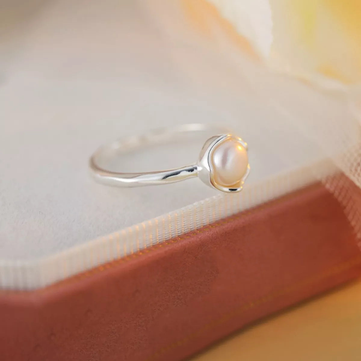 NYLD Glamour By NEWYORKLSITED: Sterling silver ring with a freshwater pearl on a soft fabric background