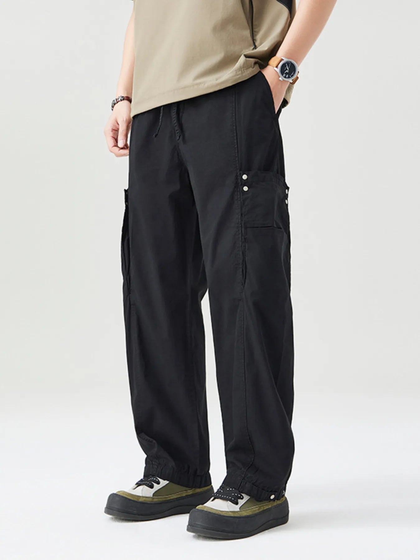 NEWYORKLISTED ATLAS MEN's COLLECTION: Person wearing black cargo pants and a beige shirt on a white background