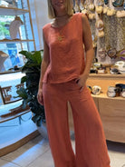 NEWYORKLISTED COMFORT COLLECTION: Person wearing a coral sleeveless top and pants in a store setting.