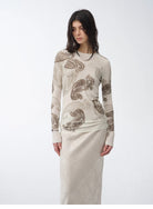 Woman wearing a long-sleeve top with a pattern on a white background