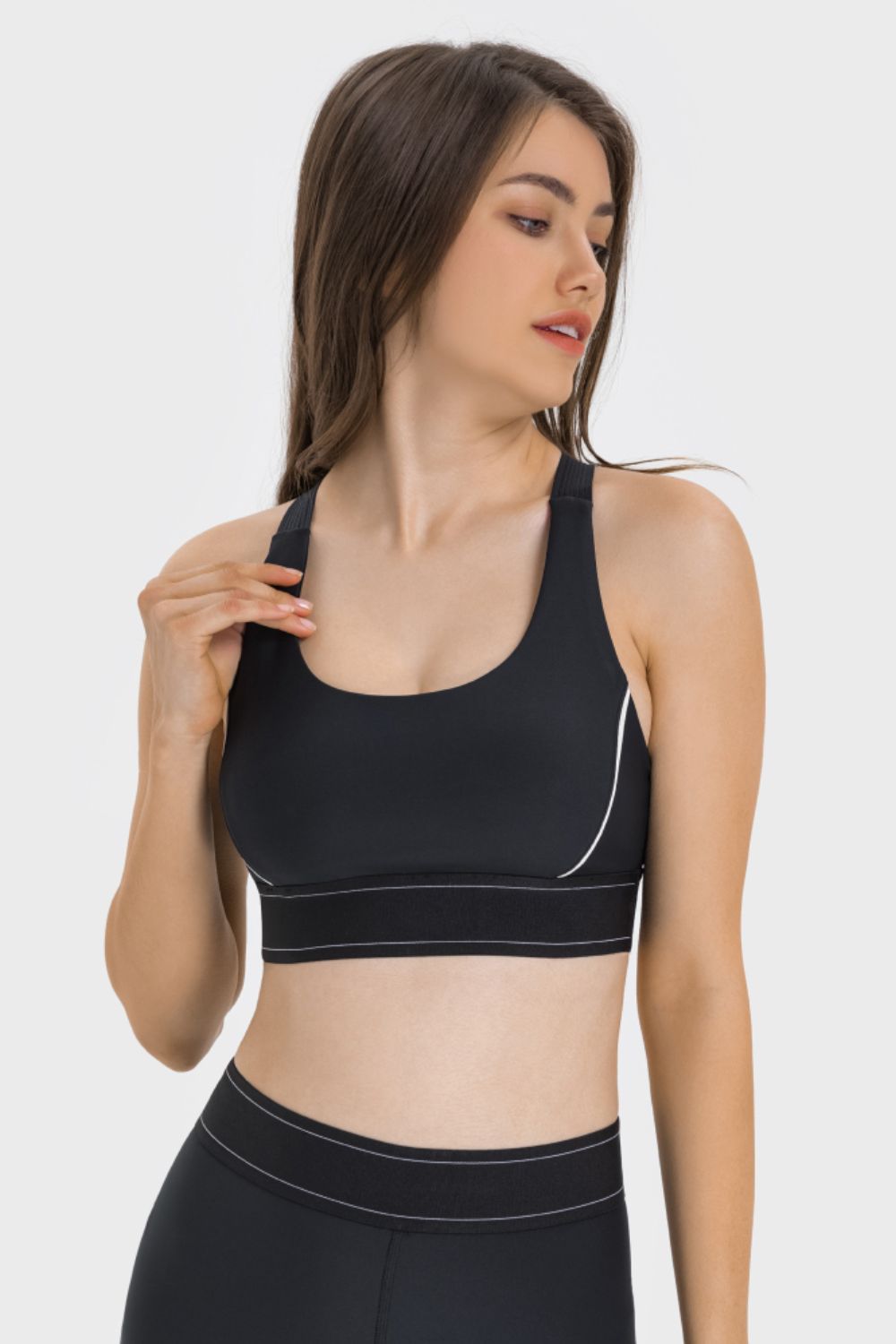 NEWYORKLISTED ACTIVEWEAR COLLECTION: Woman wearing a black sports bra and leggings on a white background