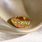 NYLD Glamour Collection by NEWYORKLISTED: Gold ring with colorful gemstones on a textured surface