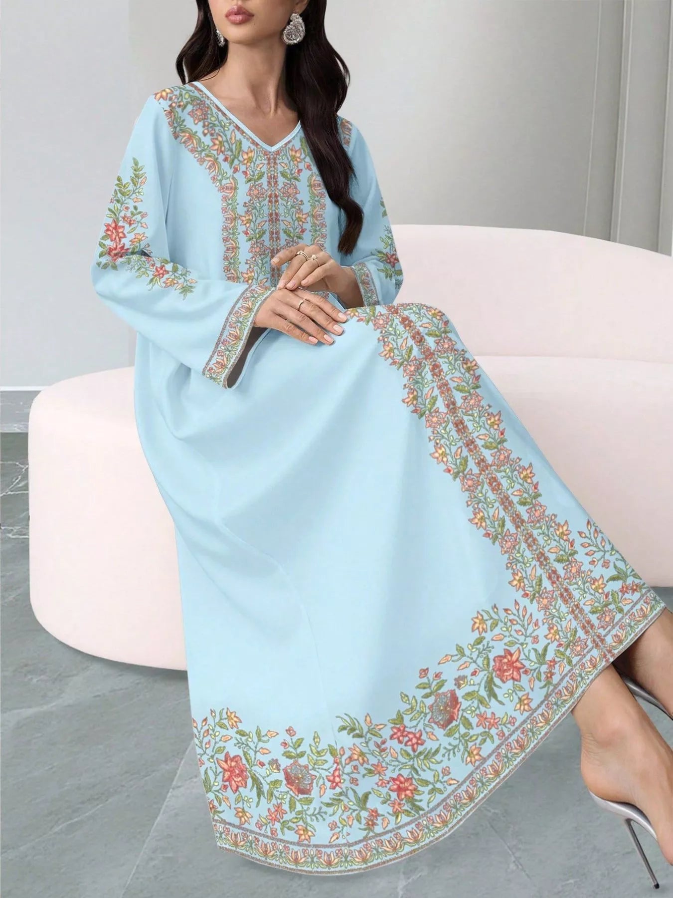 NEWYORKLISTED STYLE COLLECTION: Woman wearing a light blue embroidered dress sitting on a white chair.