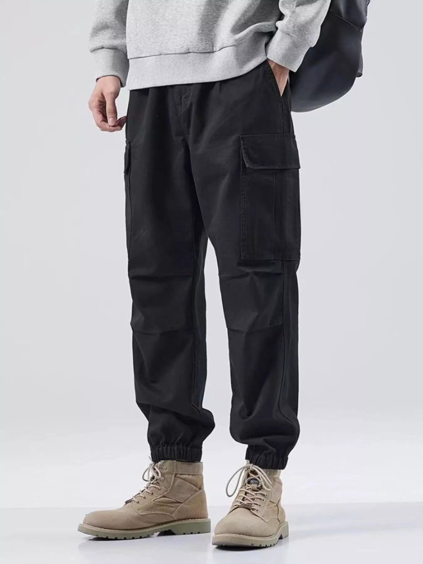 NEWYORKLISTED ATLAS MEN'S COLLECTION: Person wearing black cargo pants and beige boots on a white background