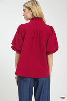 NEWYORKLISTED Style Collection: Red blouse with ruffled sleeves worn by a person on a white background