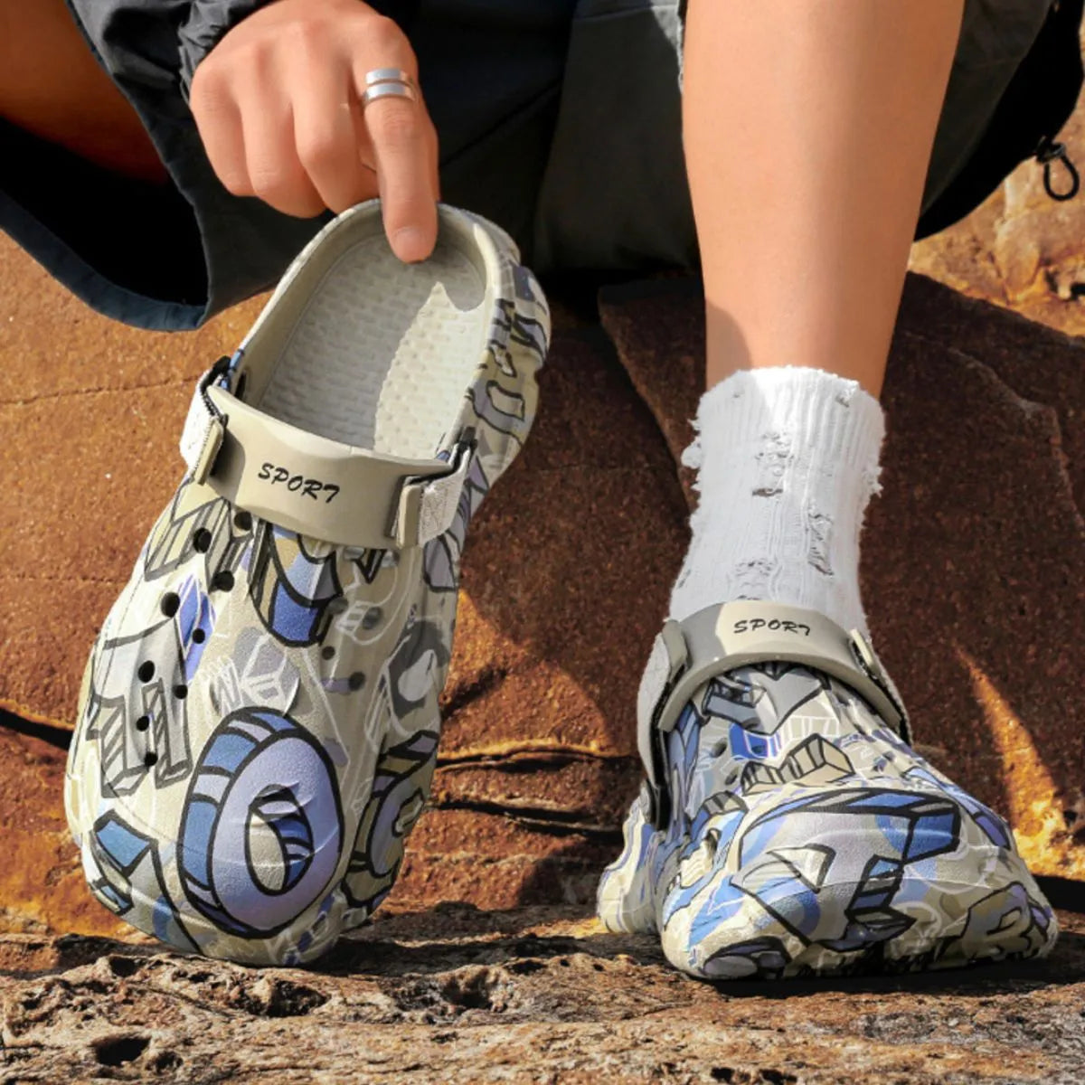NEWYORKLISTED ATLAS MEN'S COLLECTION: Person wearing patterned clogs on a rocky surface