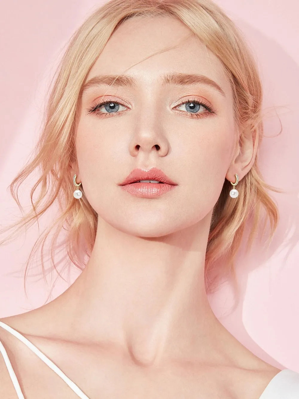 NYLD GLAMOUR COLLECTION by NEWYORKLISTED: Woman with pearl earrings against a pink background
