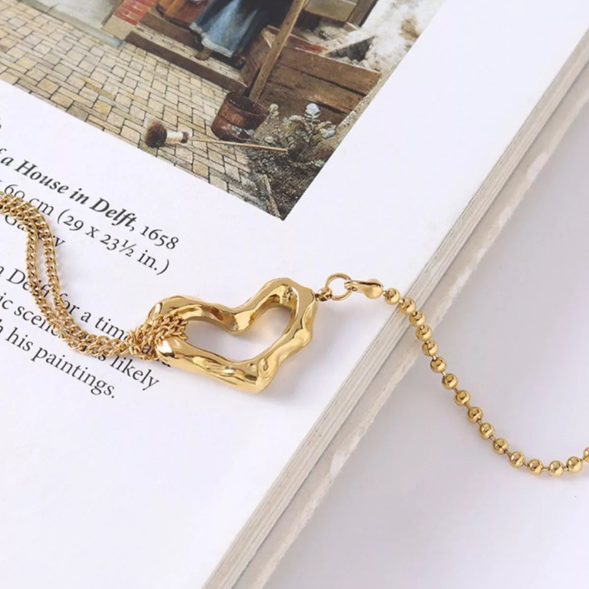 NYLD Glamour Collection by NEWYORKLISTED: Gold bracelet with a heart-shaped clasp on a book page