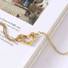NYLD Glamour Collection by NEWYORKLISTED: Gold bracelet with a heart-shaped clasp on a book page