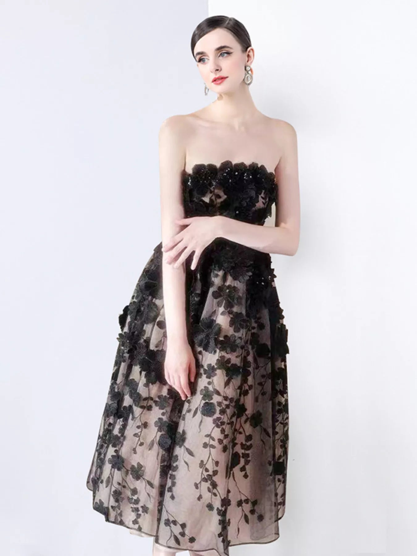 NEWYORKLISTED STYLE COLLECTION: Woman wearing a black floral strapless gown on a white background