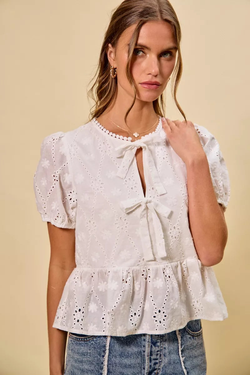 NEWYORKLISTED STYLE COLLECTION:  Woman wearing a white lace top with puffed sleeves against a beige background