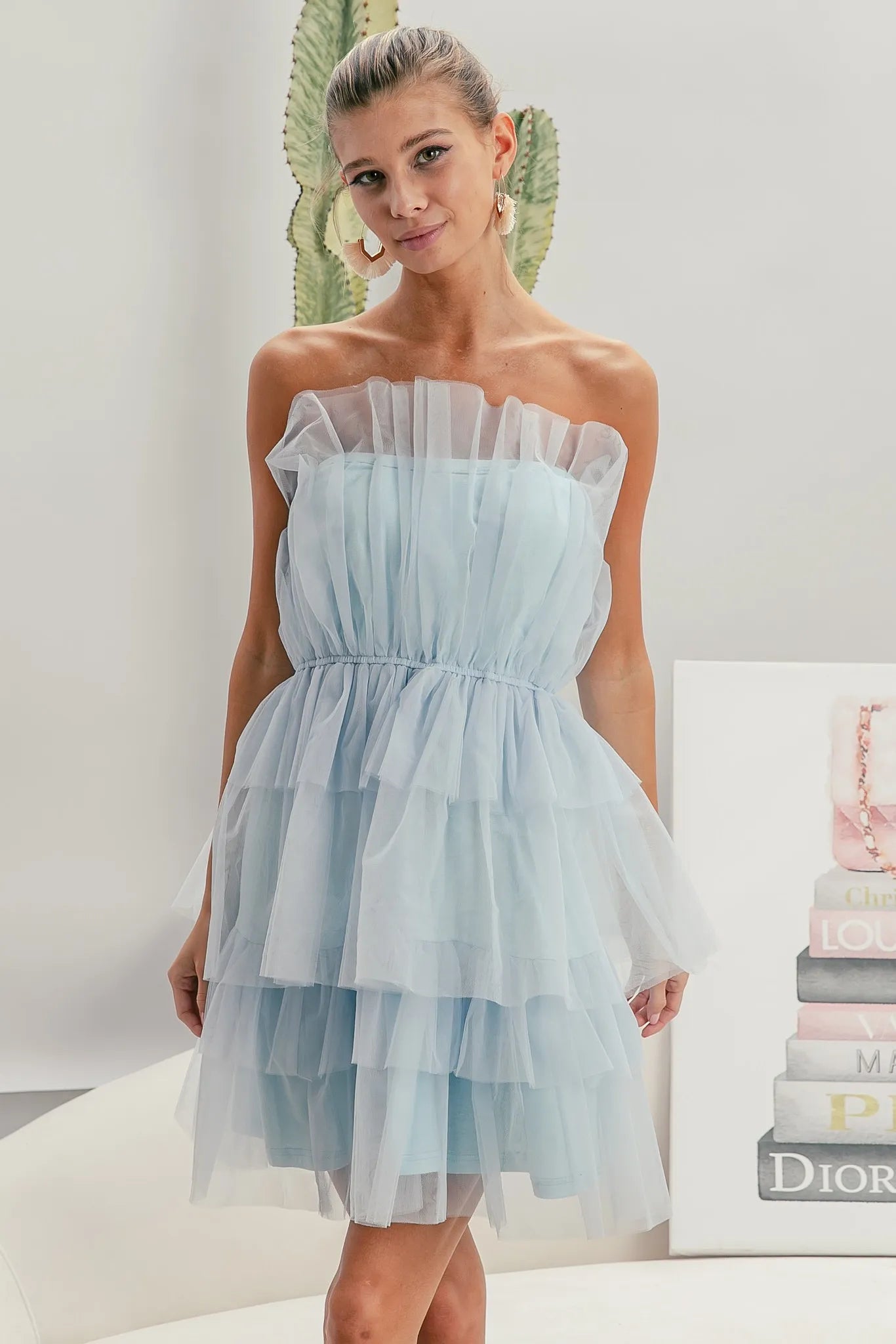 NEWYORKLISTED STYLE COLLECTION: Sleeveless Layered Organza Dress: Woman wearing a light blue strapless dress in a minimalistic setting with a 'Dior' magazine.