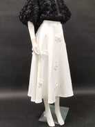 NEWYORKLISTED STYLE COLLECTION: Mannequin wearing a white dress with floral embroidery against a black background