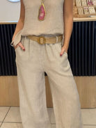 NEWYORKLISTED COMFORT COLLECTION: Person wearing a beige sleeveless top and wide-leg pants with a belt, standing indoors.