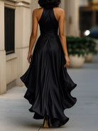 NEWYORKLISTED STYLE COLLECTION: Woman wearing a black halter neck gown walking on a sidewalk.