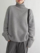 Person wearing a gray turtleneck sweater against a plain background