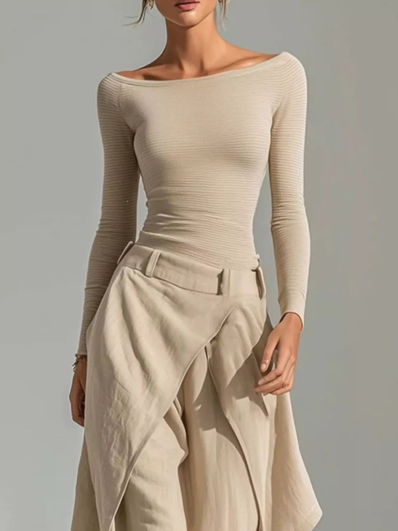 NEWYORKLISTED STYLE COLLECTION: A woman wearing a beige off-the-shoulder long-sleeve ribbed top and matching draped high-waisted trousers, photographed against a plain light gray studio background.