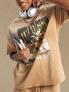 NEWYORKLISTED ATLAS MEN'S COLLECTION: Person wearing a beige t-shirt with graphic designs and holding electronic devices against a beige background