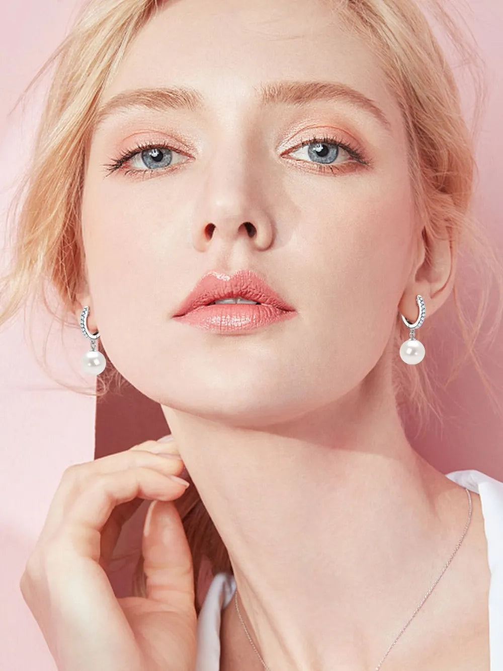 NYLD GLAMOUR COLLECTION by NEWYORKLISTED: Close-up of a person wearing pearl earrings against a pink background