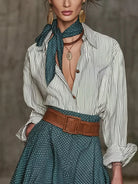 NEWYORKLISTED STYLE COLLECTION: A woman models a white and green vertically striped button-down shirt paired with a matching green polka-dot skirt, a brown leather belt, and a green polka-dot neck scarf.