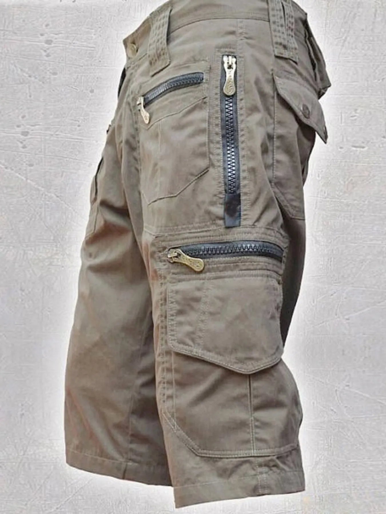 NEWYORKLISTED ATLAS MEN'S COLLECTION: Khaki cargo shorts with zippers on a light gray background