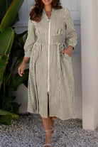 NEWYORKLISTED STYLE COLLECTION: Woman wearing a striped dress standing outdoors with plants and a white wall in the background