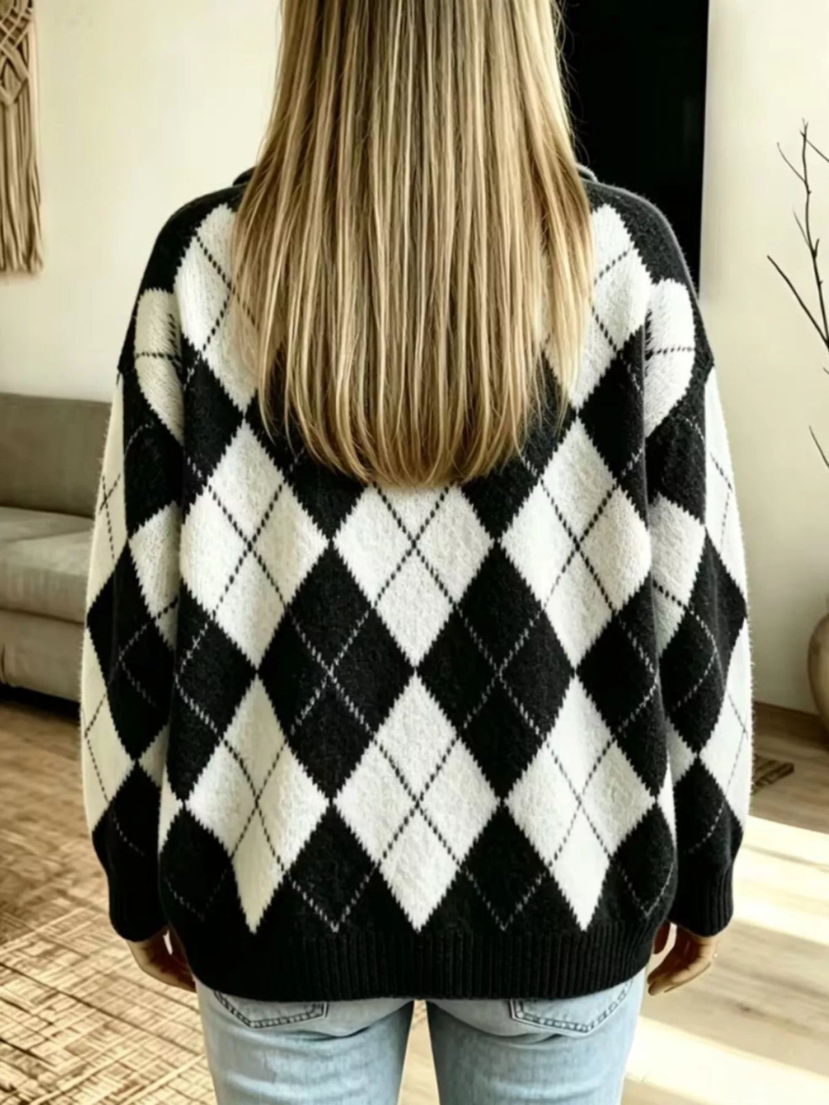 NEWYORKLISTED STYLE COLLECTION: A person viewed from behind wearing a black and white argyle knit sweater, paired with light blue jeans, in a brightly lit indoor room.