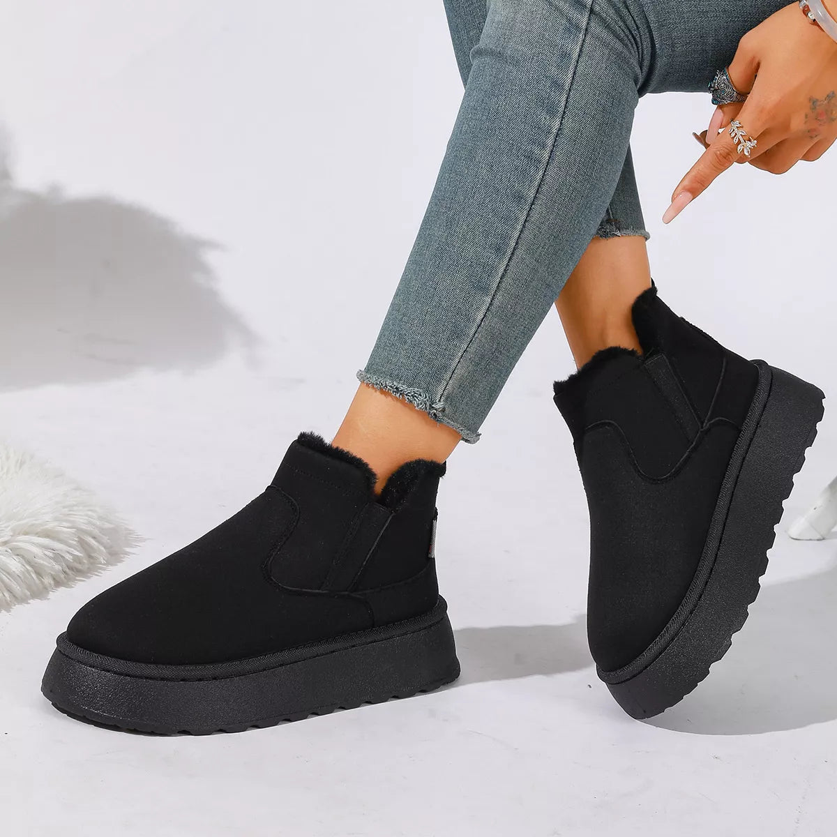 NEWYORKLISTED SHOE COLLECTION: A person wearing black platform ankle boots with a fuzzy trim, paired with light blue skinny jeans, shown against a white studio background.