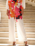 NEWYORKLSITED STYLE COLLECTION: Person wearing a colorful floral top and white pants standing on steps.