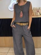 NEWYORKLISTED COMFORT COLLECTION: Person wearing a gray sleeveless top and pants with a belt, standing indoors.