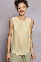 NEWYORKLISTED STYLE COLLECTION: Woman wearing a light-colored sleeveless top against a gray background