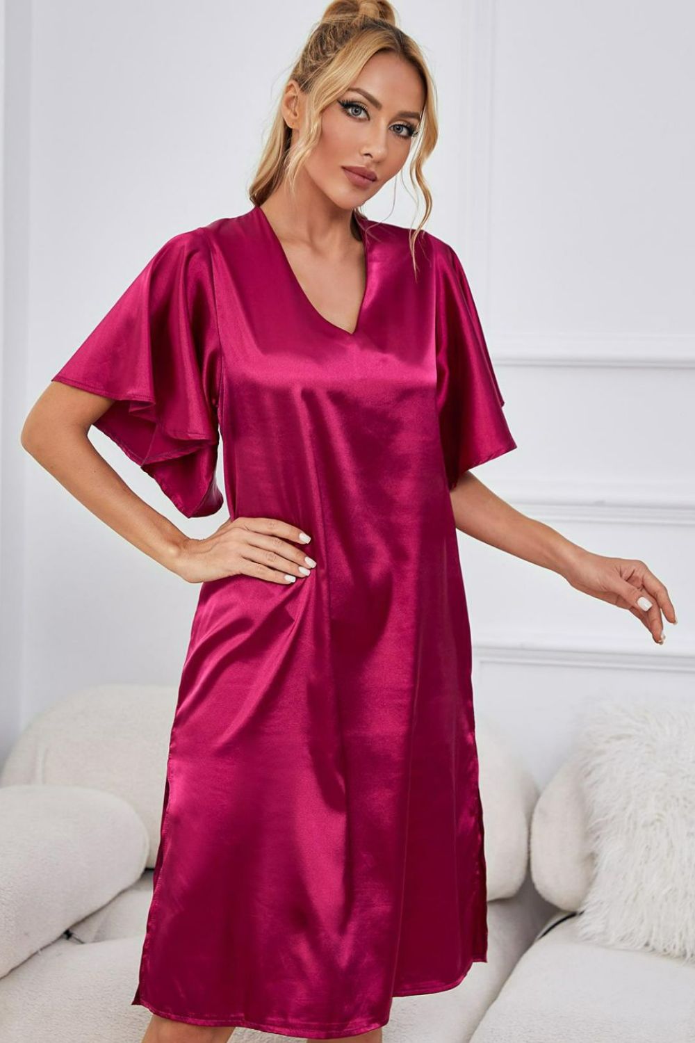 NEWYORKLISTED Intimate Apparel: Woman wearing a magenta satin nightgown in a cozy room.
