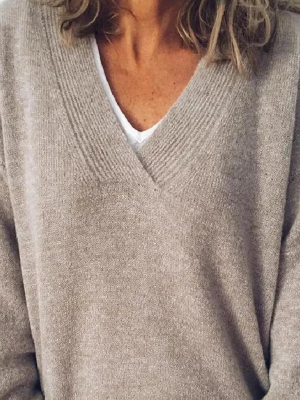 NEWYORKLISTED STYLE COLLECTION: Close-up of a person wearing a beige sweater over a white shirt.