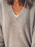 NEWYORKLISTED STYLE COLLECTION: Close-up of a person wearing a beige sweater over a white shirt.