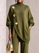 NEWYORKLISTED STYLE COLLECTION:  A woman models an olive green knit turtleneck sweater with oversized decorative gold buttons and matching wide-leg knit pants, holding a small metallic gold handbag against a neutral textured wall.