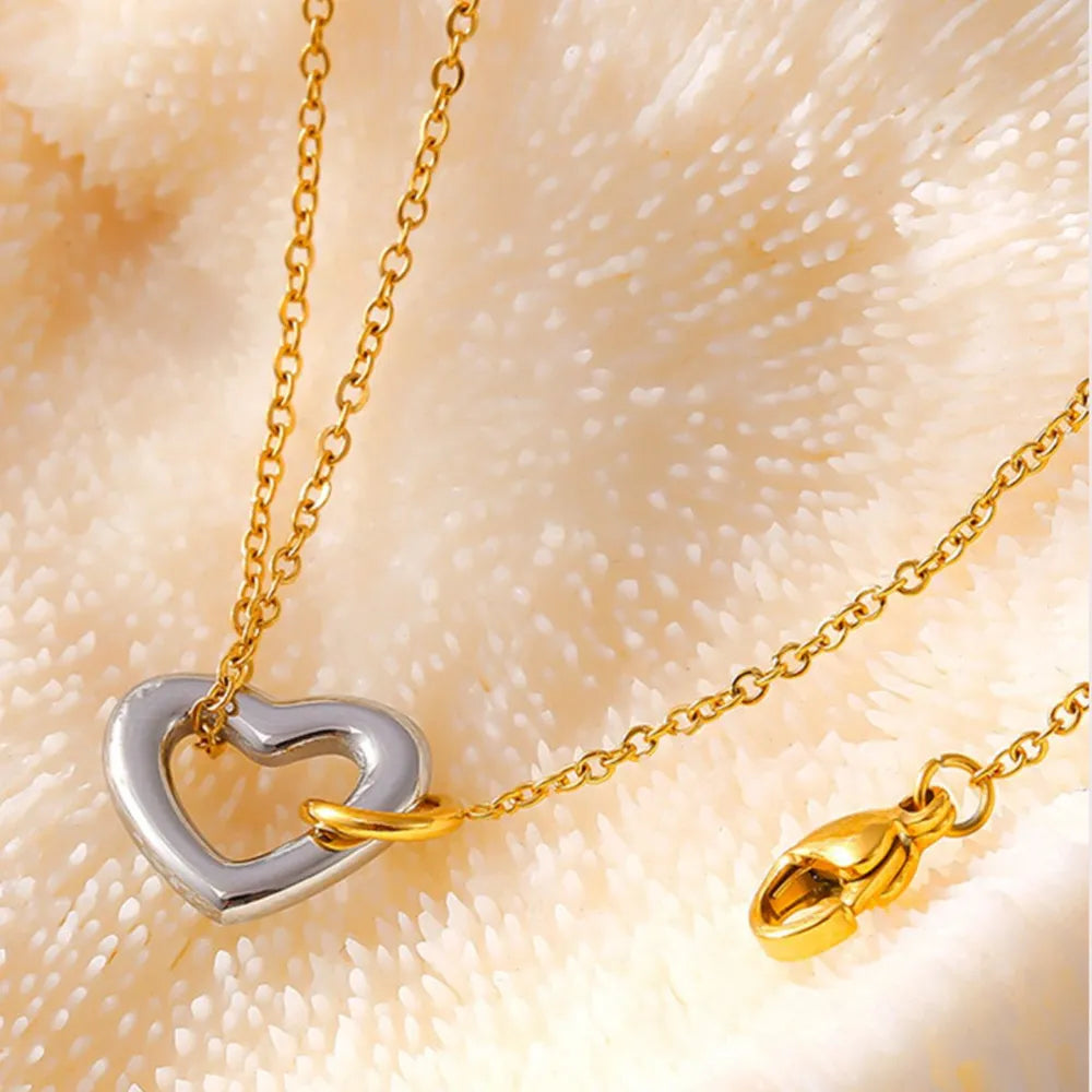 NEWYORKLISTED Valentine's Day Specials: Gold and silver heart-shaped necklace on a textured beige background