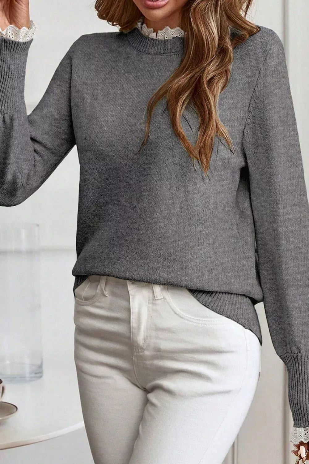 NEWYORKLISTED STYLE COLLECTION: Person wearing a gray sweater and light-colored pants indoors.
