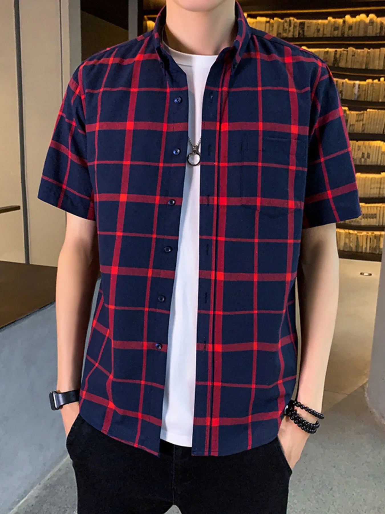 Person wearing a blue and red plaid shirt over a white shirt.