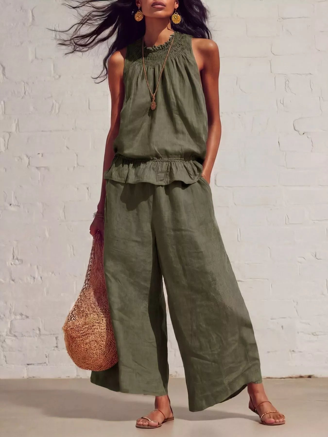 NEWYORKLISTED STYLE COLLECTION: Woman wearing an olive green jumpsuit against a white brick wall.