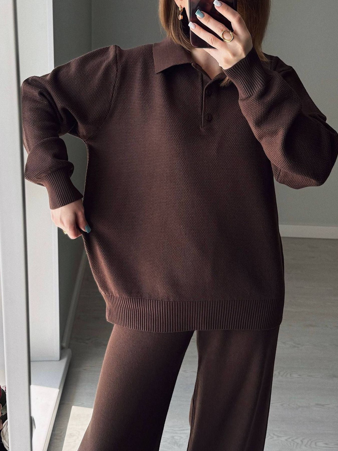 NEWYORKLISTED Comfort Collection: Person wearing a brown sweater and pants in a minimal indoor setting.