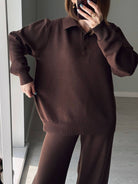 NEWYORKLISTED Comfort Collection: Person wearing a brown sweater and pants in a minimal indoor setting.