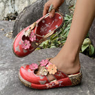 NEWYORKLISTED SHOE COLLECTION: Red floral sandals being worn on a stone surface with greenery in the background