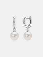 NYLD GLAMOUR COLLECTION by NEWYORKLISTED: Pair of pearl earrings with silver hooks on a light gray background