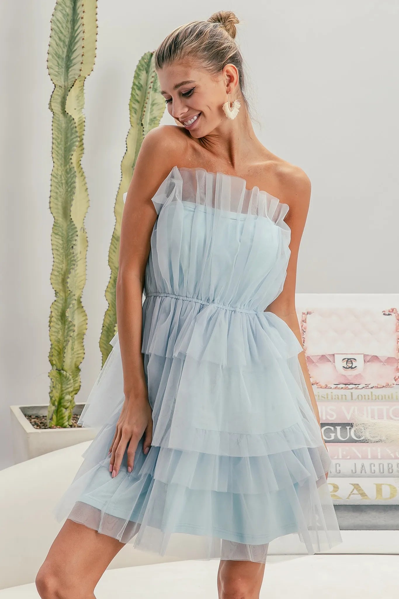 NEWYORKLISTED STYLE COLLECTION: Sleeveless Layered Organza Dress: Woman wearing a light blue strapless dress with a blurred indoor background