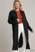 NEWYORKLISTED STYLE COLLECTION: Woman wearing a black long coat over a red top and white pants on a gray background