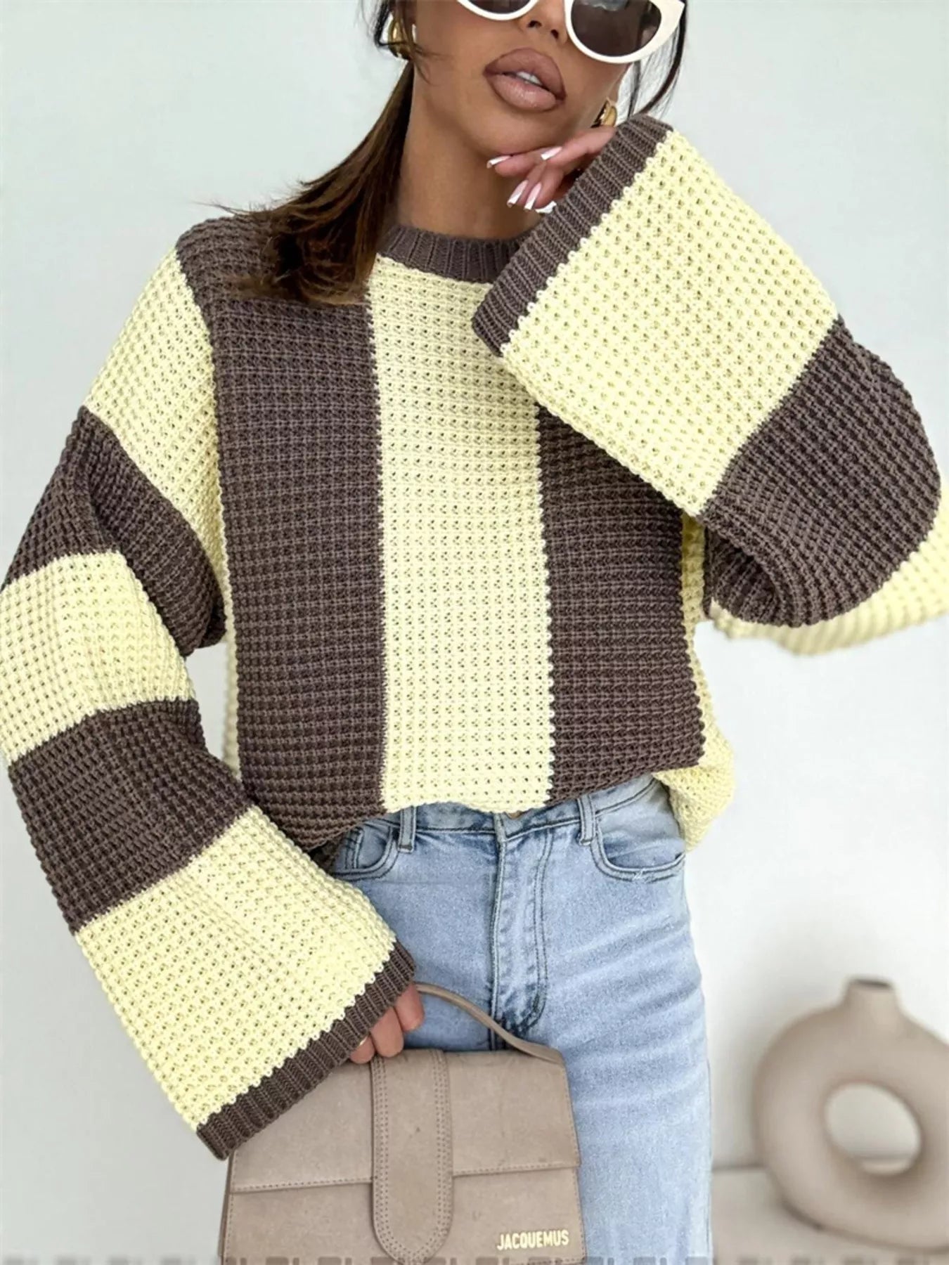 NEWYORKLISTED STYLE COLLECTION: Person wearing a striped sweater with brown and yellow colors, standing against a light gray background.