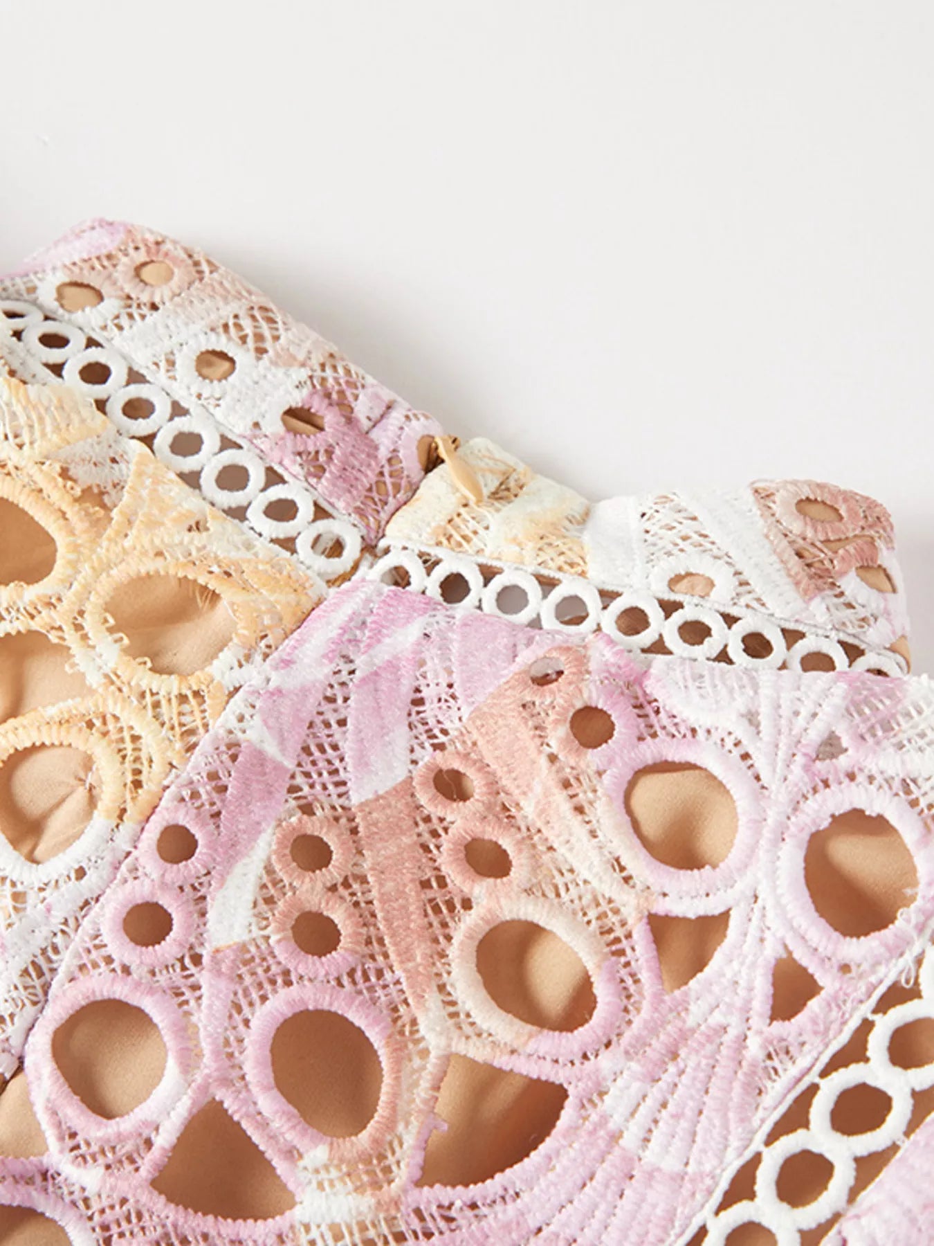 Close-up of lace fabric in pastel colors on a white background