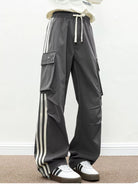 NEWYORKLISTED ATLAS MEN's COLLECTION: Person wearing gray cargo pants with white stripes and white sneakers on a plain background